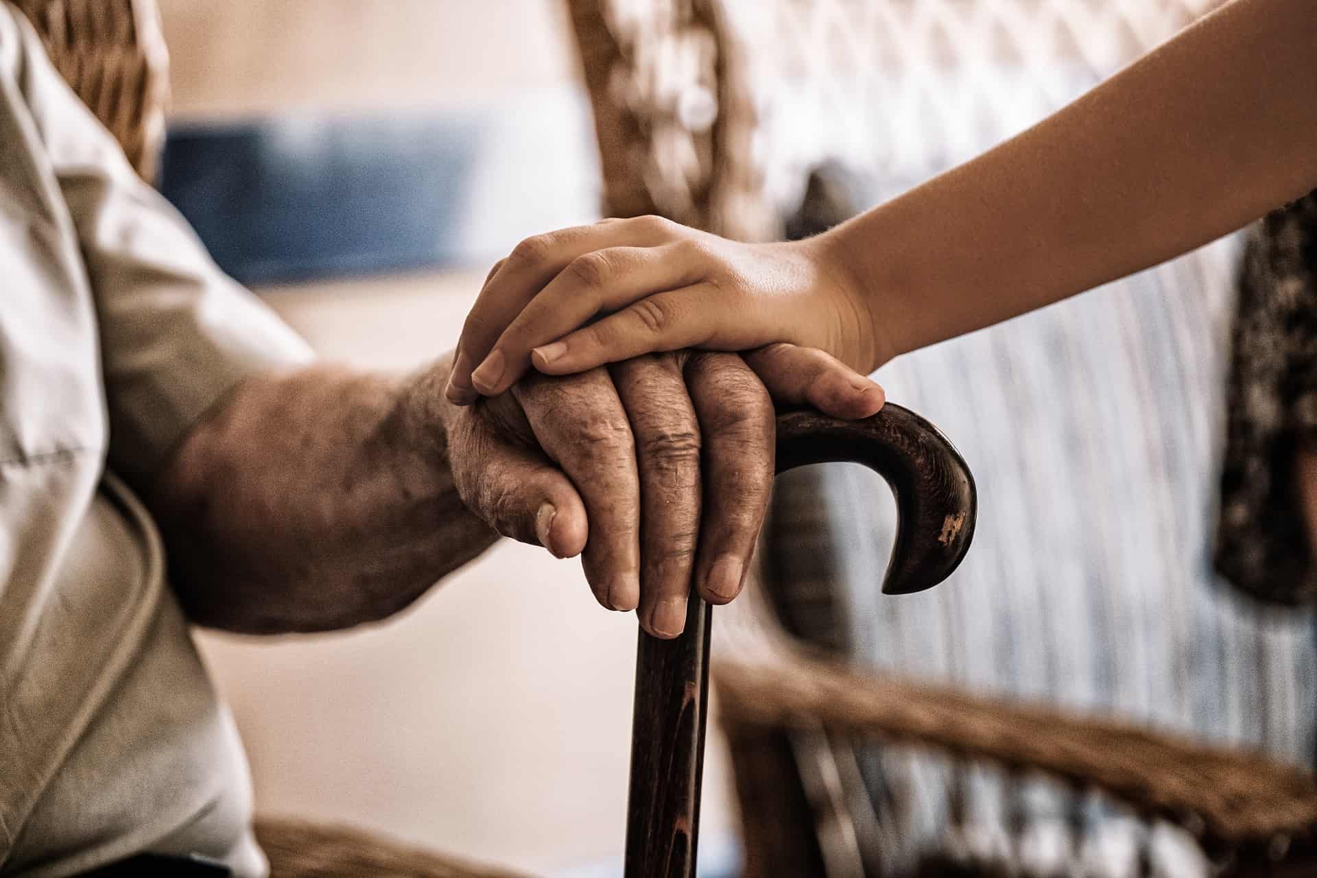 una mano anciana y una joven estrechadas